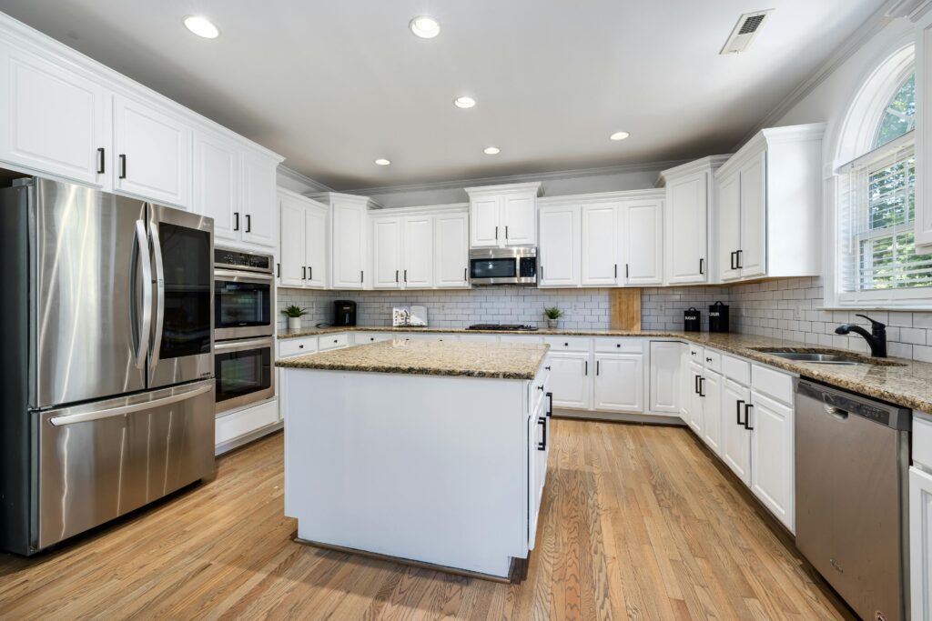 Modern kitchen featuring white cabinets, granite countertops, and stainless steel appliances.