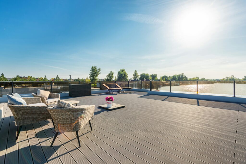 Spacious outdoor deck with rattan furniture and lounging area under bright summer sun.