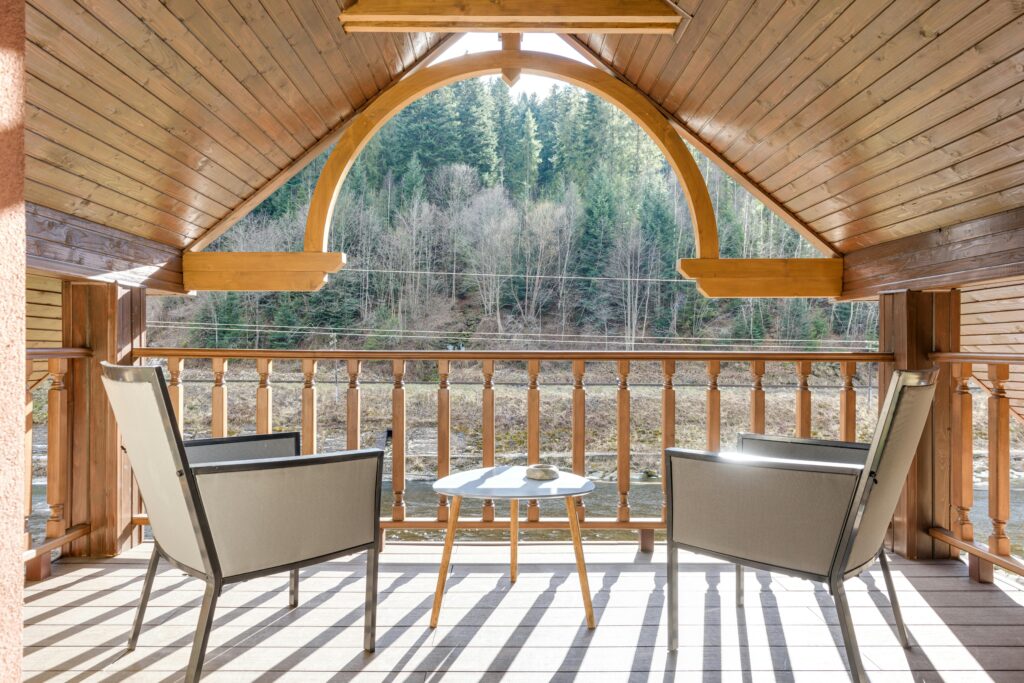 A serene balcony with chairs and table overlooking a tranquil forest setting, ideal for relaxation.